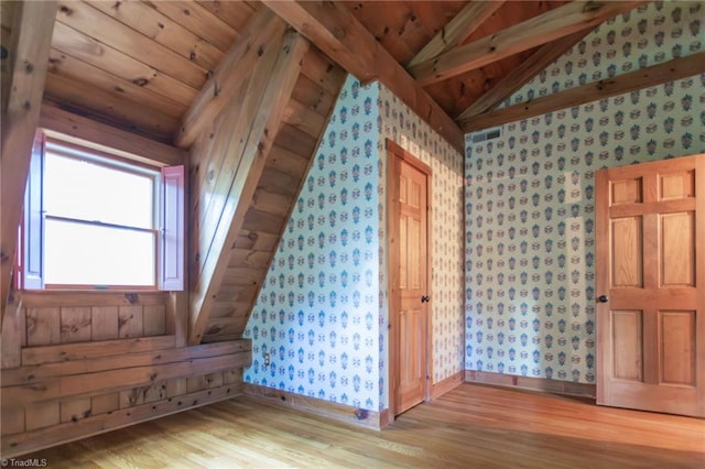 additional living space with wallpapered walls, baseboards, lofted ceiling with beams, wood ceiling, and wood finished floors