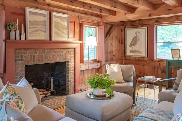 sitting room with a brick fireplace, wood walls, beam ceiling, and a healthy amount of sunlight