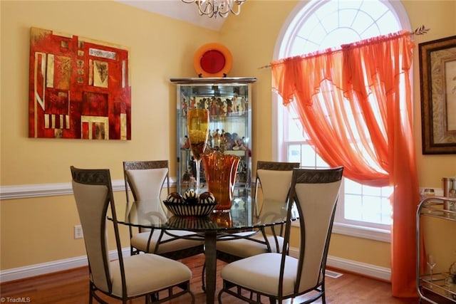 dining space featuring wood-type flooring and a notable chandelier