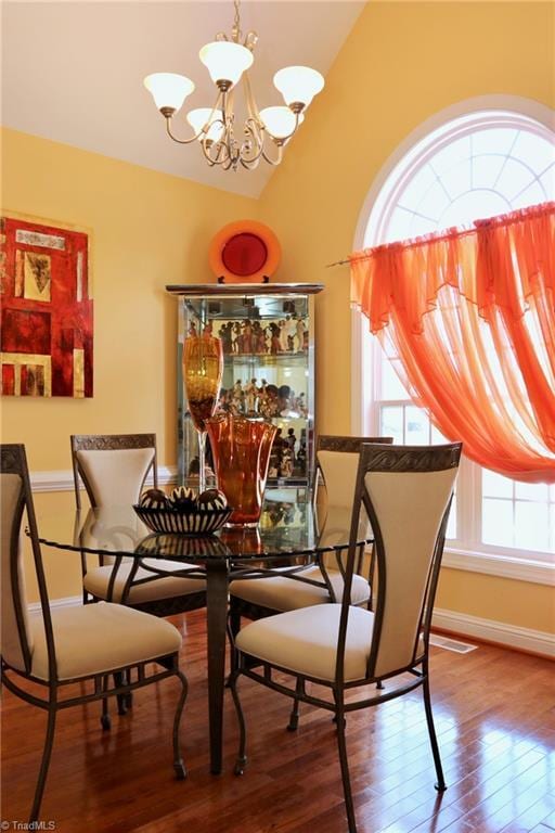 dining area featuring a notable chandelier, vaulted ceiling, and wood-type flooring