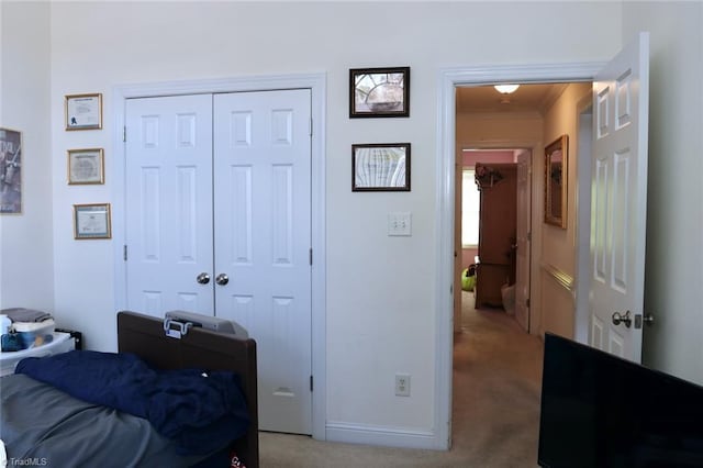 bedroom with crown molding, light colored carpet, and a closet