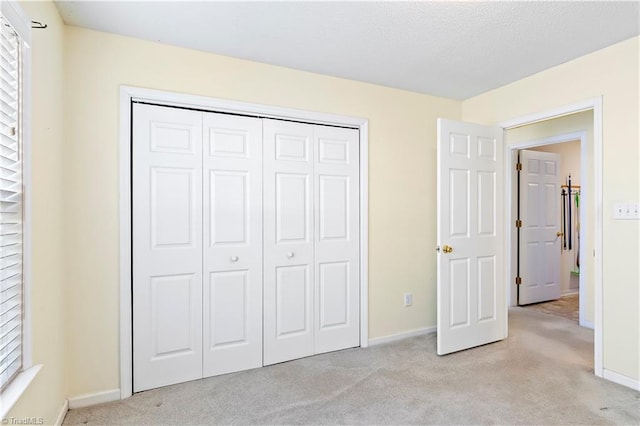 unfurnished bedroom with light carpet and a closet