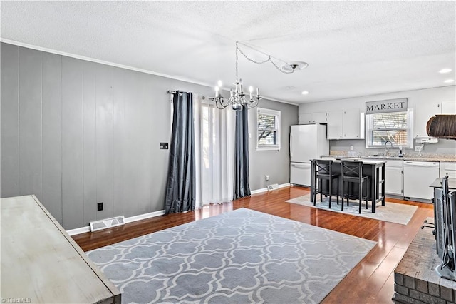 interior space with sink, a textured ceiling, white fridge, a notable chandelier, and hardwood / wood-style floors