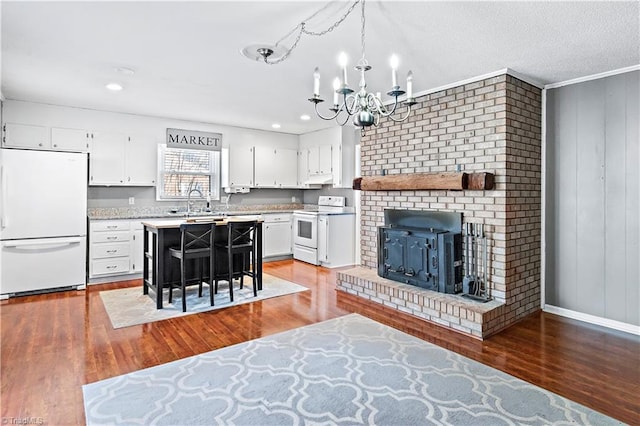 kitchen featuring decorative light fixtures, wood-type flooring, white cabinets, a kitchen breakfast bar, and white appliances