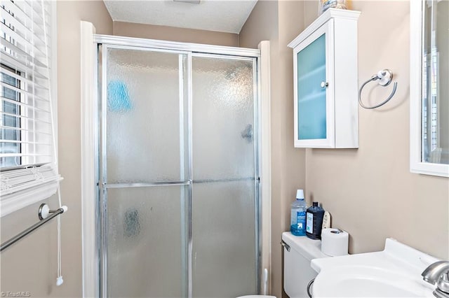 bathroom with toilet, sink, and a shower with door