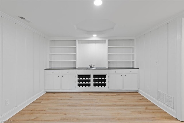 bar featuring built in shelves, white cabinetry, and light hardwood / wood-style flooring