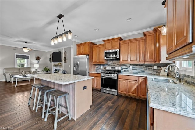 kitchen with appliances with stainless steel finishes, dark wood-type flooring, sink, and a kitchen island