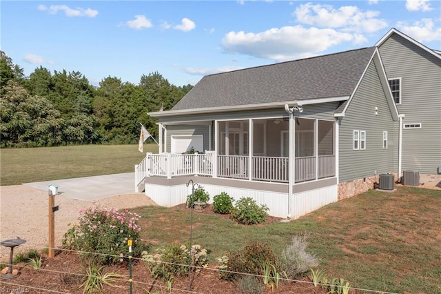 back of property with central AC unit, a sunroom, a yard, and a patio area