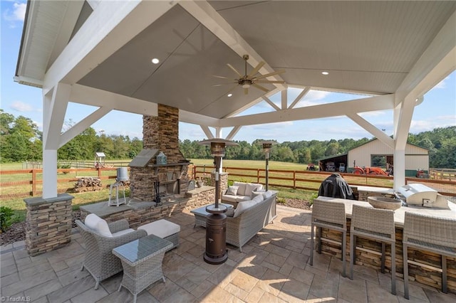 view of patio with ceiling fan, an outdoor living space with a fireplace, and a gazebo