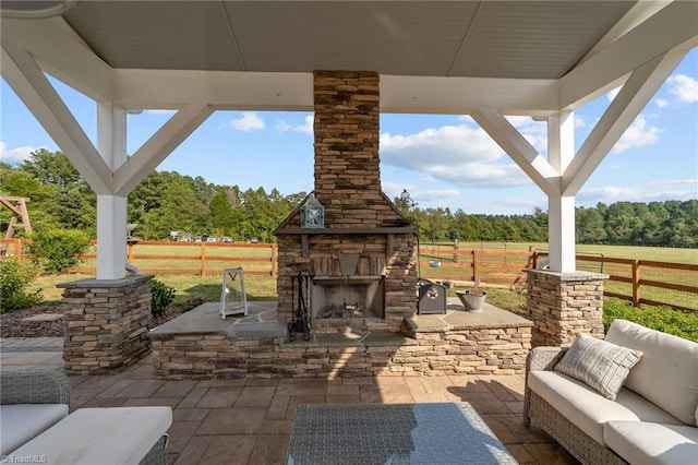 view of patio with an outdoor living space with a fireplace and a rural view