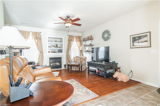 living room featuring ceiling fan, wood-type flooring, and built in shelves