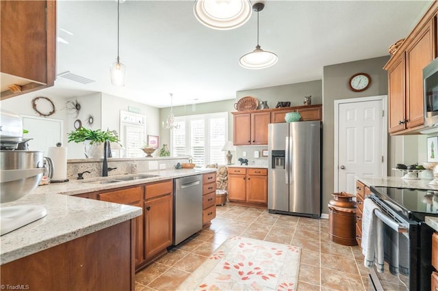 kitchen featuring pendant lighting, stainless steel appliances, light stone countertops, and sink