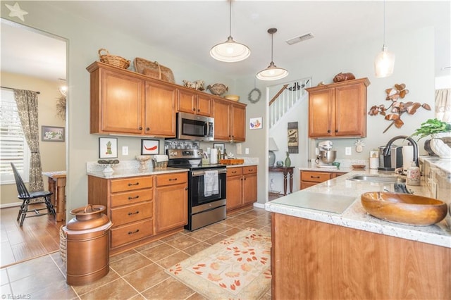 kitchen featuring hanging light fixtures, stainless steel appliances, light stone countertops, sink, and light tile patterned floors