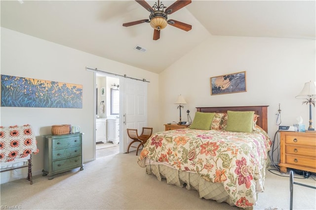 bedroom featuring vaulted ceiling, ceiling fan, connected bathroom, a barn door, and light carpet