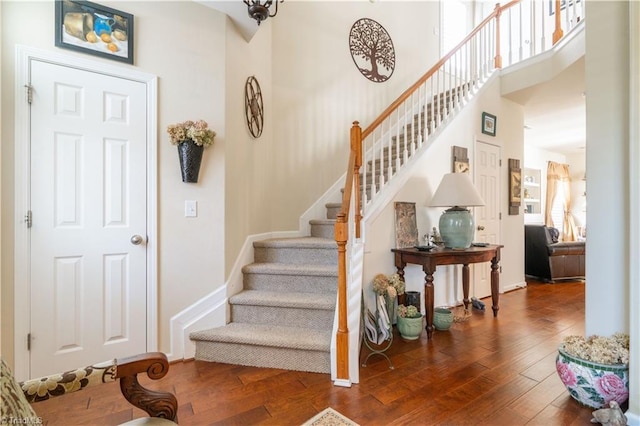 stairway with hardwood / wood-style floors and a high ceiling