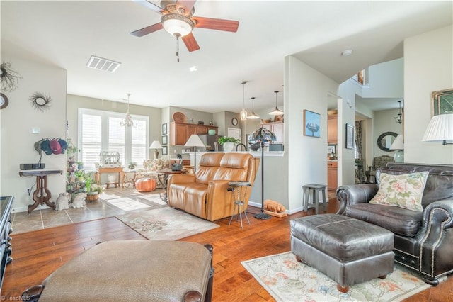 living room with ceiling fan with notable chandelier and light hardwood / wood-style flooring