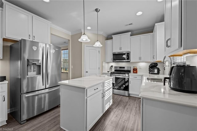 1318 Reading Ct, Burlington, NC 27217 - kitchen with appliances with stainless steel finishes, ornamental molding, wood finished floors, a center island, and white cabinetry
