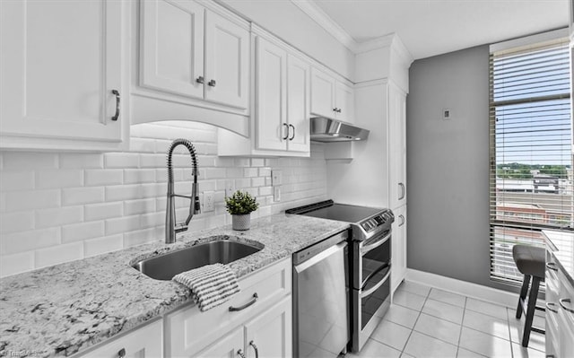 1101 N Elm St Unit 902, Greensboro, NC 27401 - kitchen with under cabinet range hood, stainless steel appliances, a sink, white cabinets, and baseboards