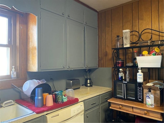 kitchen featuring a sink, dishwasher, gray cabinetry, and light countertops