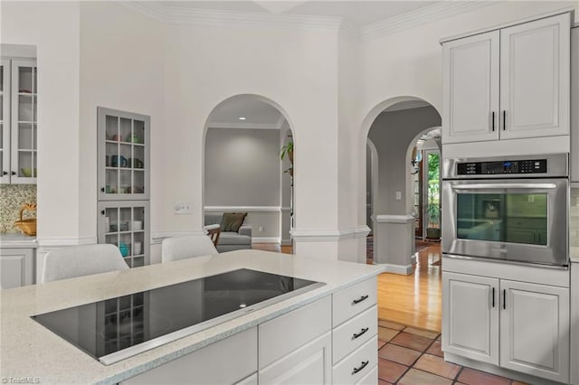 2020 La Dora Dr, High Point, NC 27265 - kitchen featuring oven, black electric stovetop, crown molding, arched walkways, and light tile patterned floors