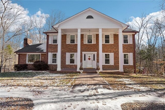 greek revival inspired property with a porch and a front lawn