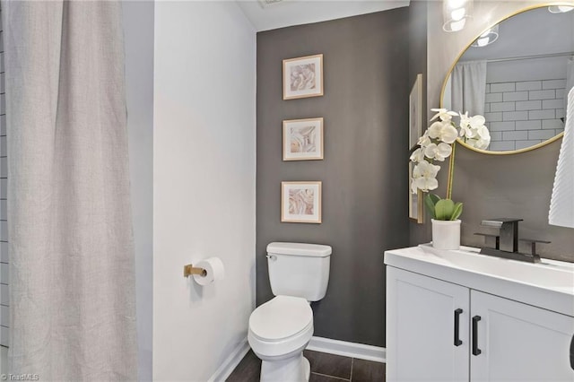 bathroom with baseboards, toilet, and vanity
