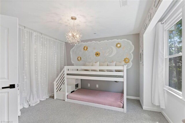 carpeted bedroom with a chandelier and baseboards