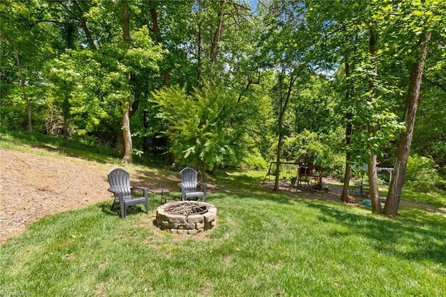 view of green lawn with an outdoor fire pit and a playground