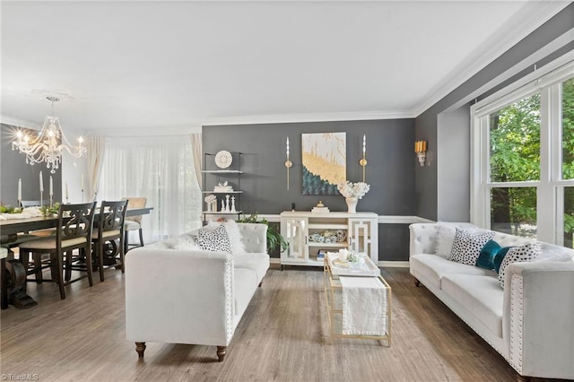 living area with crown molding, a chandelier, wood finished floors, and baseboards