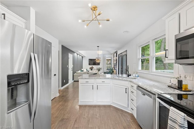 kitchen featuring stainless steel appliances, a chandelier, a sink, and a peninsula