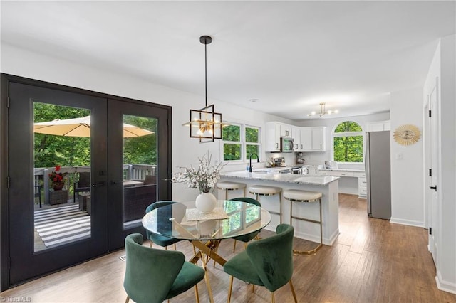 dining area featuring french doors, a chandelier, light wood-style floors, and baseboards