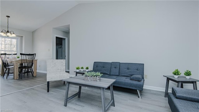 interior space featuring baseboards, light wood-type flooring, lofted ceiling, and an inviting chandelier