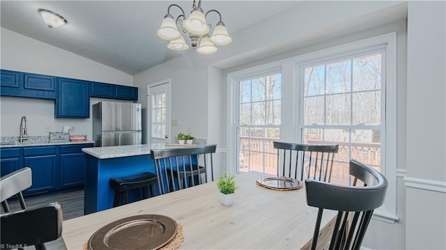 dining space with an inviting chandelier, vaulted ceiling, plenty of natural light, and a textured ceiling