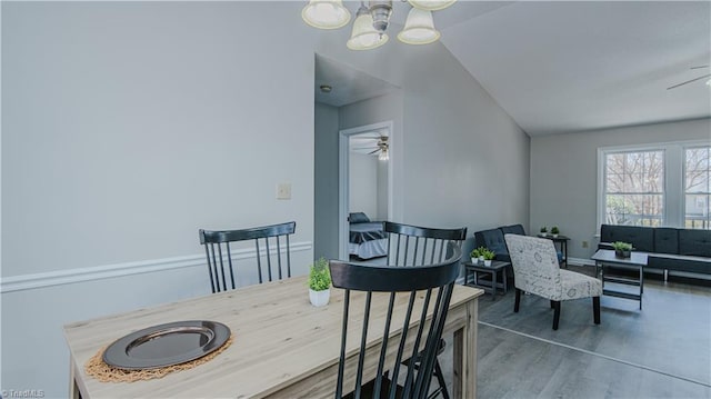 dining space featuring lofted ceiling, wood finished floors, and ceiling fan with notable chandelier