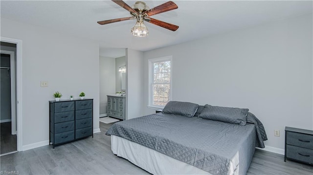 bedroom featuring a ceiling fan, wood finished floors, baseboards, and connected bathroom