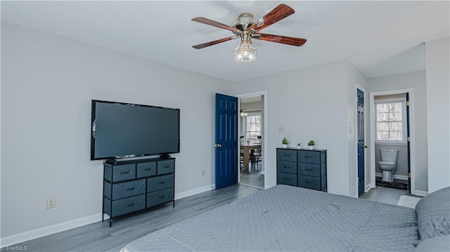 bedroom with connected bathroom, baseboards, wood finished floors, and a ceiling fan