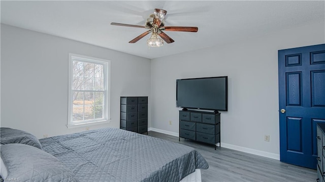 bedroom featuring ceiling fan, baseboards, and wood finished floors