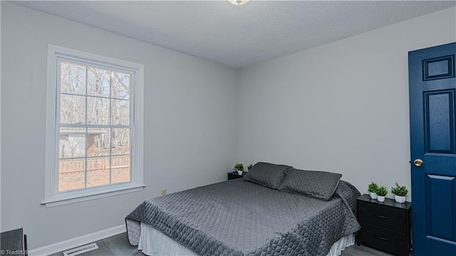 bedroom featuring multiple windows, wood finished floors, visible vents, and a textured ceiling