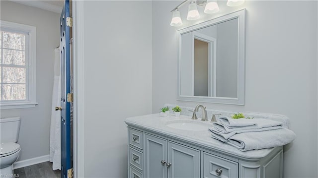 full bathroom featuring baseboards, toilet, wood finished floors, and vanity