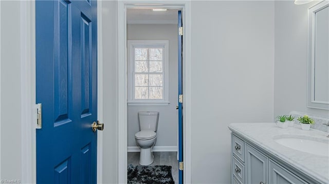 bathroom with toilet, vanity, and baseboards