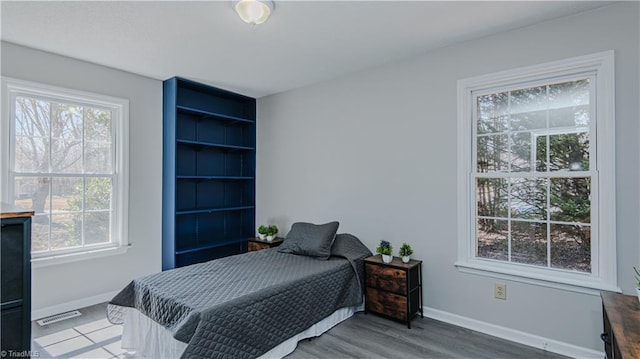 bedroom with wood finished floors, baseboards, and visible vents