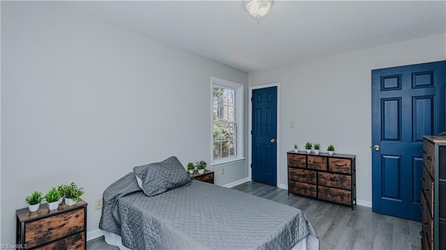 bedroom featuring baseboards, a textured ceiling, and wood finished floors