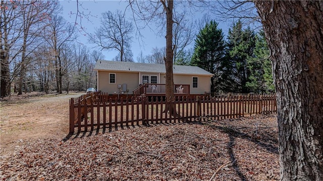 back of property with a wooden deck and a fenced front yard