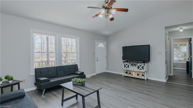 living area with a ceiling fan, lofted ceiling, wood finished floors, and baseboards