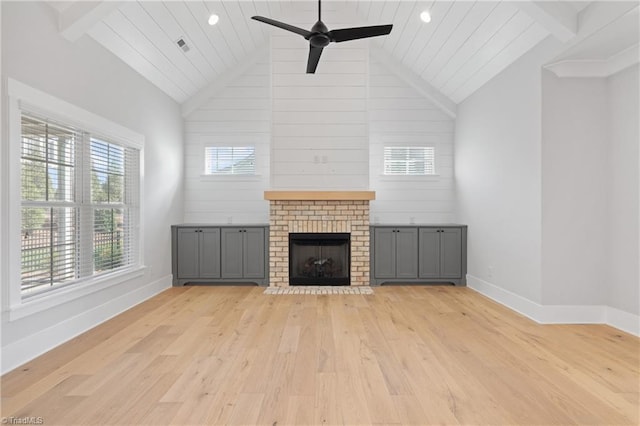 unfurnished living room featuring wooden walls, high vaulted ceiling, ceiling fan, a fireplace, and light hardwood / wood-style flooring