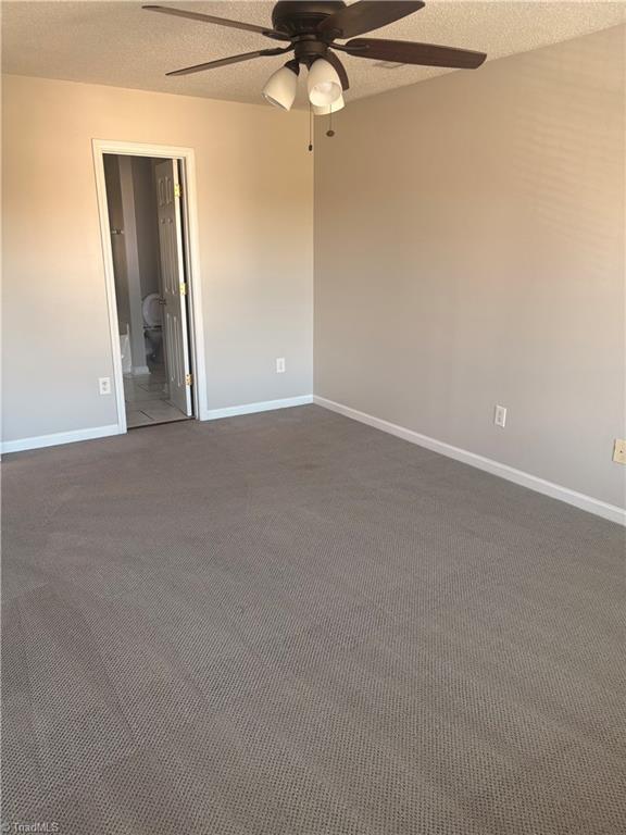 carpeted spare room featuring a textured ceiling and ceiling fan