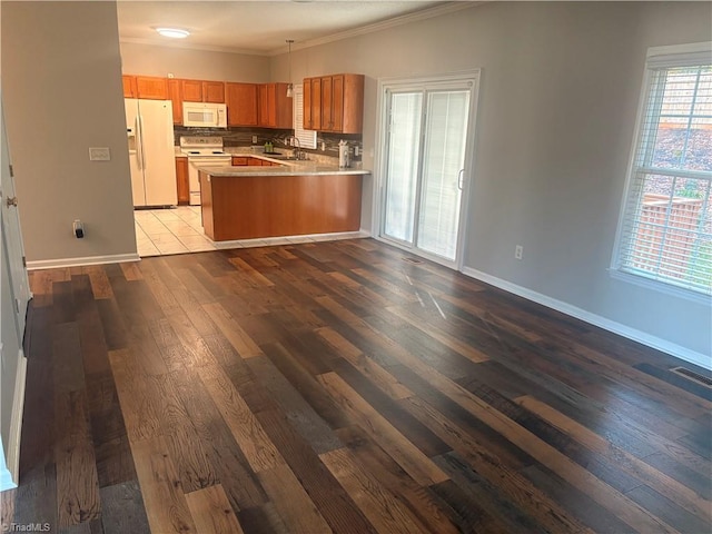 kitchen with kitchen peninsula, sink, ornamental molding, light wood-type flooring, and white appliances