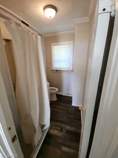 bathroom featuring hardwood / wood-style flooring, crown molding, toilet, and a shower with curtain