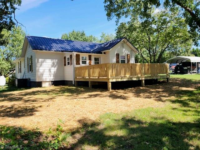 back of property featuring a carport and a wooden deck