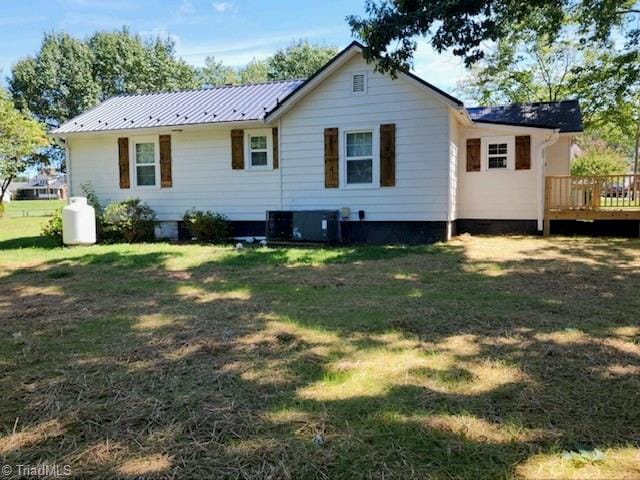 back of property featuring a deck, a yard, and central AC